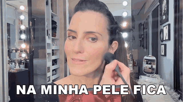 a woman applying makeup in front of a mirror with the words na minha pele fica