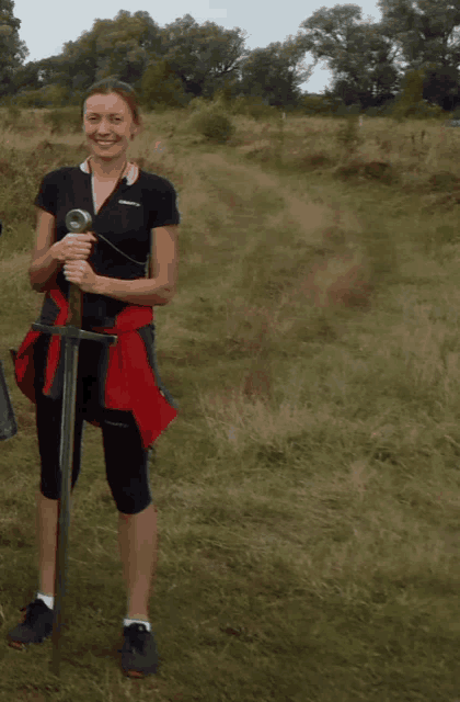 a woman holding a sword in a field wearing a black shirt that says craft