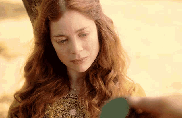 a woman with red hair and a yellow dress looks down