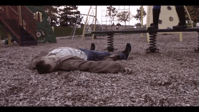 a man laying on the ground in a playground