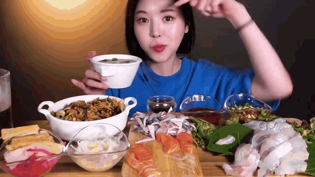 a woman in a blue shirt is sitting at a table eating a variety of food