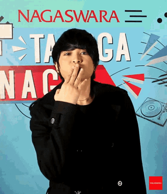 a man covering his mouth with his hand in front of a sign that says nagaswara