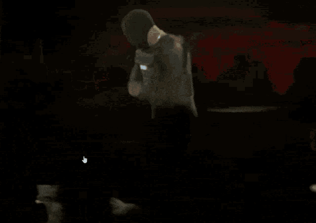 a man in a hooded jacket is dancing in front of a crowd of people .