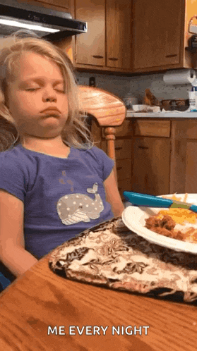 a little girl is sitting at a table with her eyes closed and a plate of food with the words me every night written on it