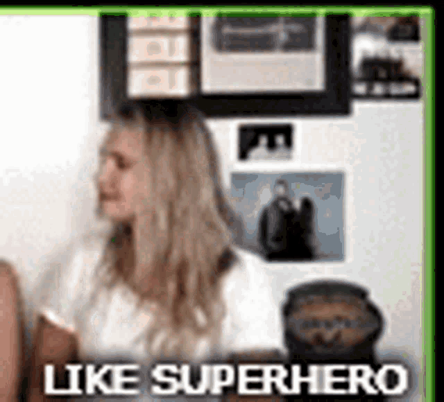 a woman is sitting in front of a wall with pictures and the words `` like superhero '' written on it .