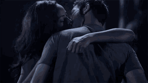 a man and a woman are kissing in the dark .