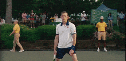 a man holding a tennis racquet on a tennis court in front of a crowd