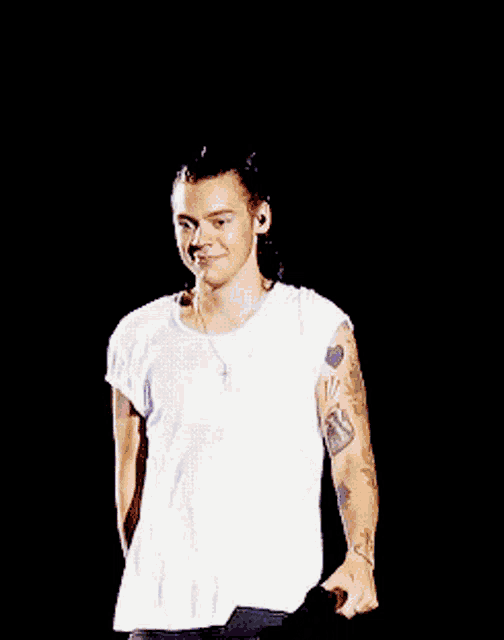 a man with a tattoo on his arm is laughing and wearing a white shirt