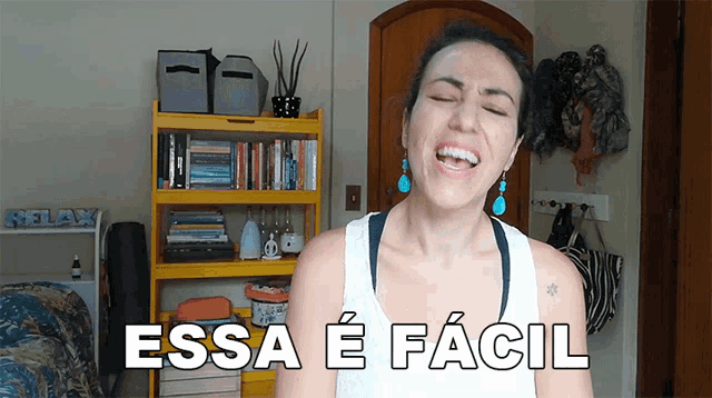 a woman laughs in front of a yellow bookshelf with the words essa e facil written on it