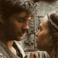 a man and a woman are looking at each other with a sword in the background .