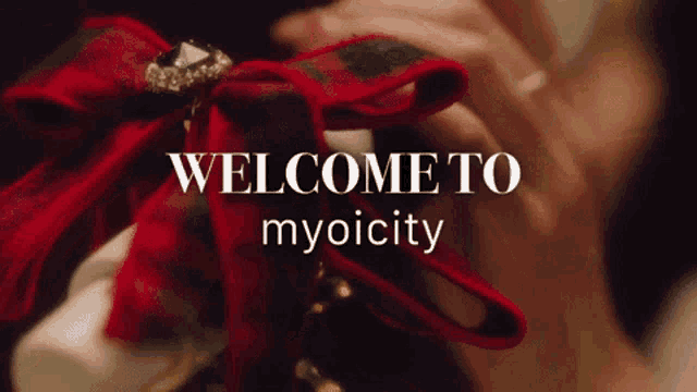 a woman is holding a red bow with the words welcome to myoicity written on it