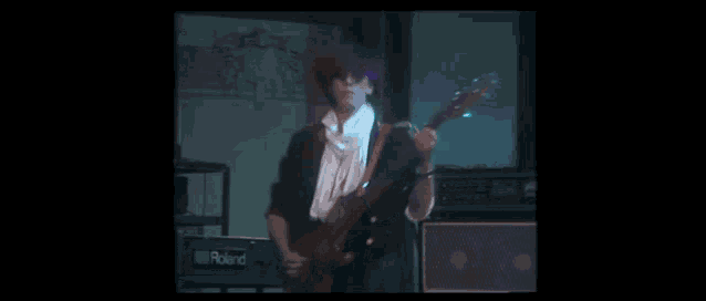 a man is playing a bass guitar on a stage in a dark room .
