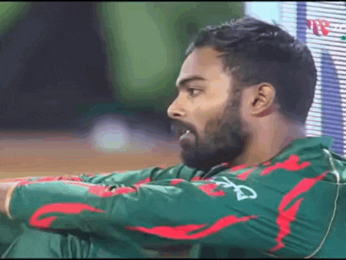 a man with a beard is wearing a green and red shirt with the letter a on it