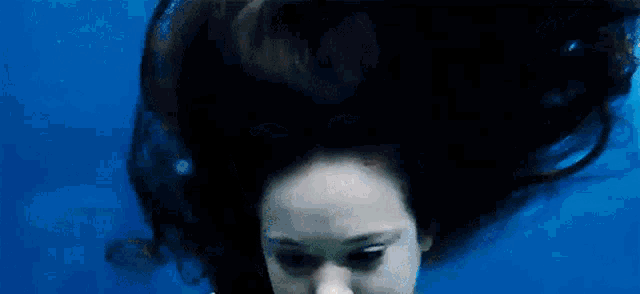 a woman with long black hair is swimming underwater in the ocean .