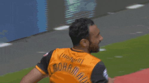 a man in a soccer uniform is running on a red field .