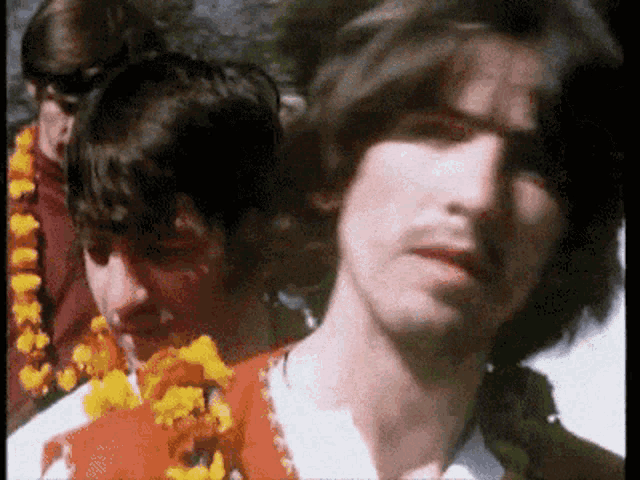 a group of men are standing next to each other and one of them is wearing a flower garland around his neck .