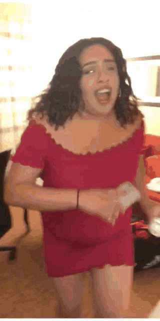 a woman in a red off the shoulder dress is singing