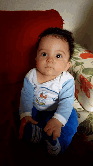a baby sitting on a couch wearing a shirt that says ' butterfly ' on it