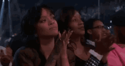 a group of women are sitting in a stadium and clapping .
