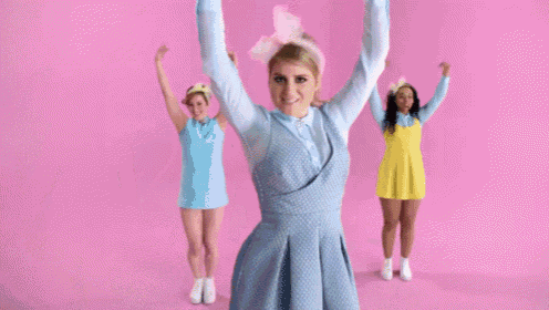 a group of girls are dancing in front of a pink background