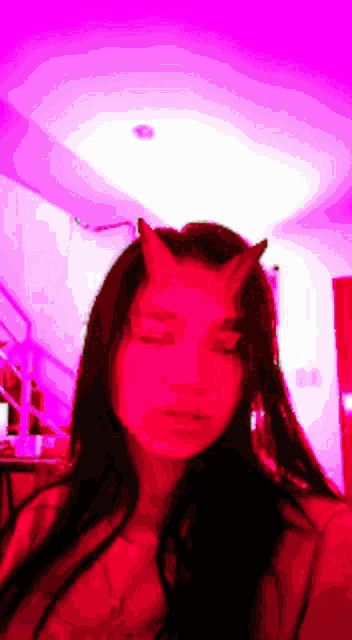 a girl with horns on her head is taking a selfie