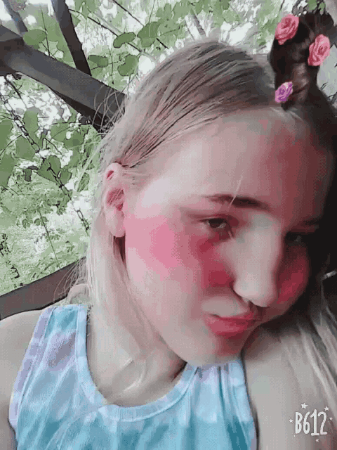 a girl with pink paint on her face and the number b612 on the bottom right