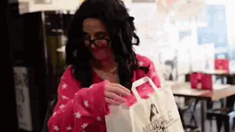 a woman in a wig and glasses is holding a bag that says abercrombie