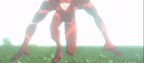 a man in a red superhero suit is standing in the grass .
