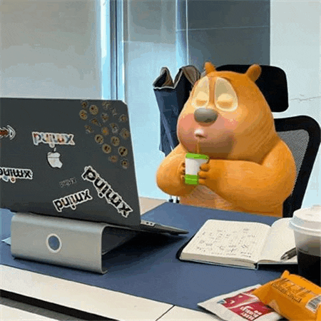 a cartoon bear is sitting at a desk in front of a laptop computer .