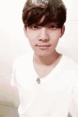 a young man wearing a white shirt and a necklace