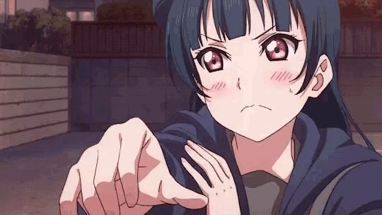 a girl in a blue hoodie is pointing at the camera with her finger .
