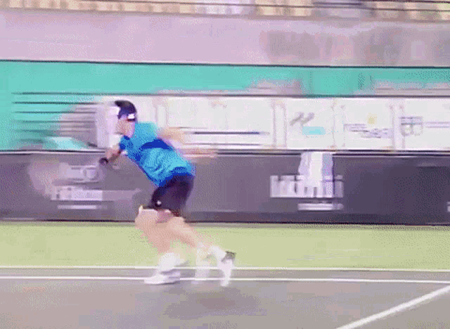 a man in a blue shirt and black shorts is playing tennis on a court