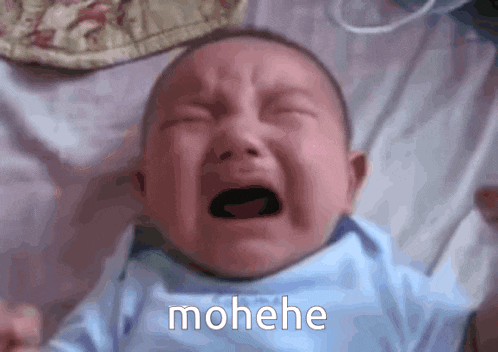 a baby in a blue shirt is crying with the word mohehe written below it
