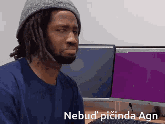 a man sitting in front of a computer with the words nebud picinda agn written on the screen