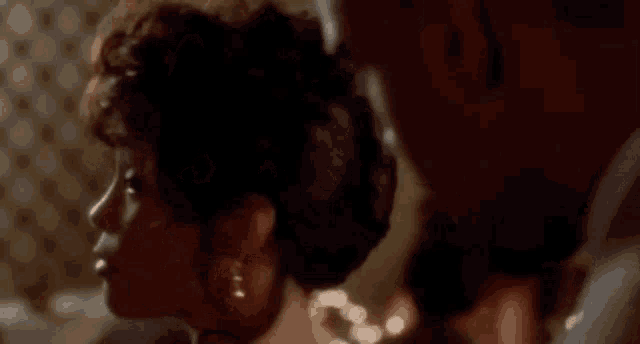 a woman with curly hair is smiling at a man in a dark room .