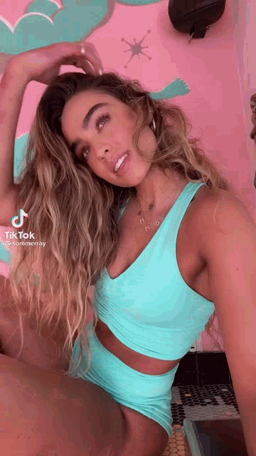 a woman in a blue tank top and shorts is taking a selfie .