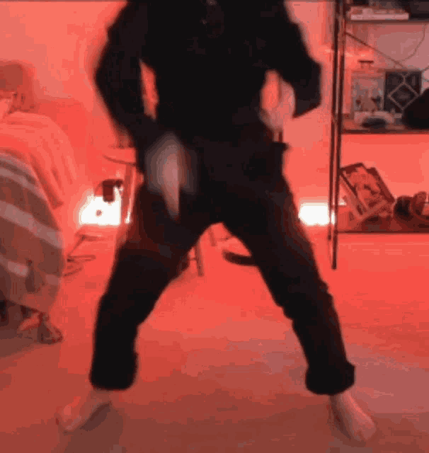 a person is dancing in a room with red lights behind them