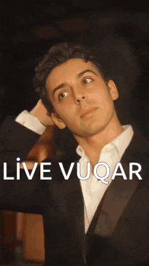 a man in a suit and white shirt is looking up with the words live vuqar below him