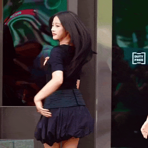 a woman in a black skirt is dancing in front of a duty free sign
