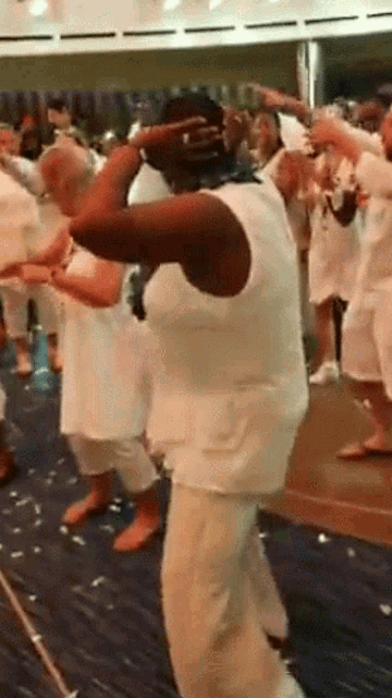 a group of people in white shirts are dancing on a stage