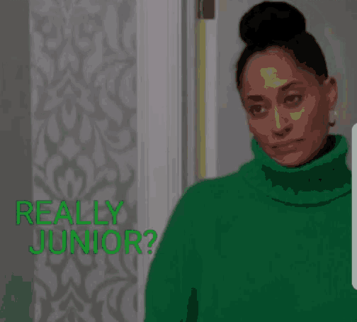 a woman in a green sweater is standing in front of a door and asking , `` really junior ? ''