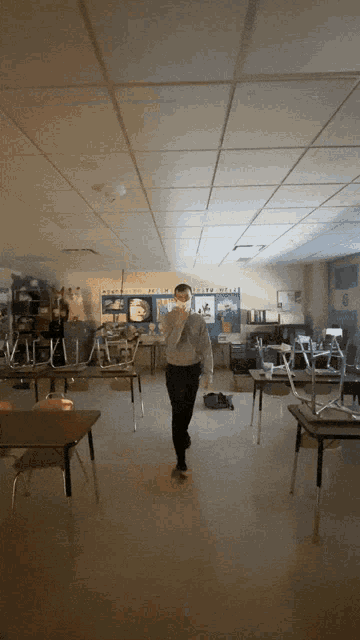 a man walking through a classroom with a bulletin board that says ' science world ' on it