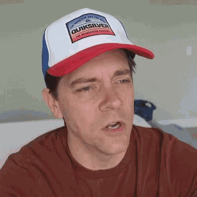 a man wearing a red , white and blue quiksilver hat .