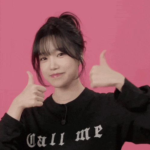 a girl wearing a black shirt that says call me is giving a thumbs up