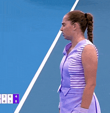 a woman in a purple striped shirt stands on a blue tennis court