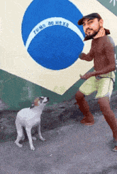 a man playing with a dog in front of a flag that says " rumo ao hexa "