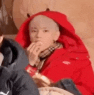 a man wearing a red hooded jacket is sitting on a couch .