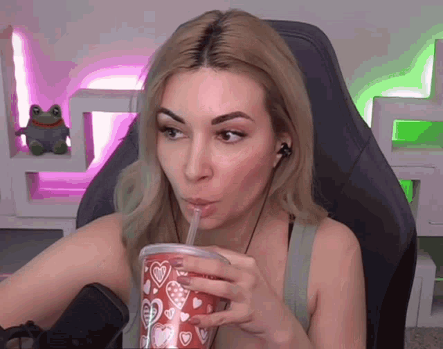 a woman is drinking through a straw from a cup that has hearts on it