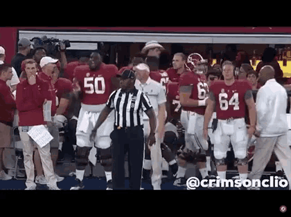 a group of football players are standing in front of a referee wearing a jersey with the number 50 on it
