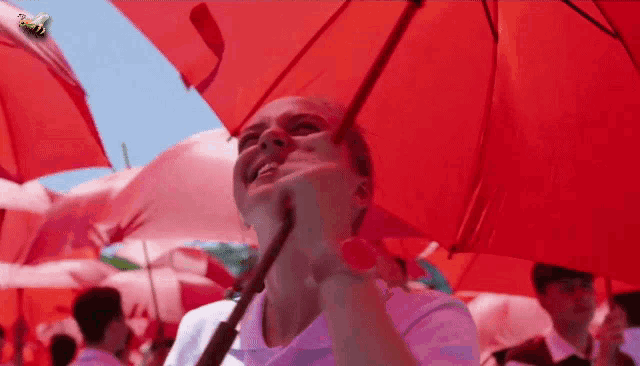 a woman holding a red umbrella with a bee on it